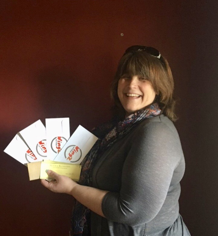 Jennifer Pandolfo, Center for Vision Loss, holding up restaurant gift certificates as she prepares to give them to clients.